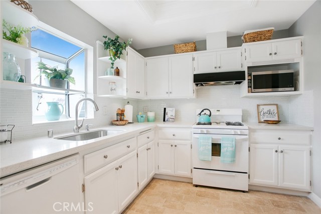 Cheerful sunlight through a mini-bay window over the sink complements this pristine white upgraded Kitchen.