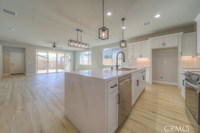 The immaculate kitchen has a large quartz waterfall edge island, quartz countertops, LG Stainless Steel appliances, real wood soft close cabinets and tiled backsplash. ??
