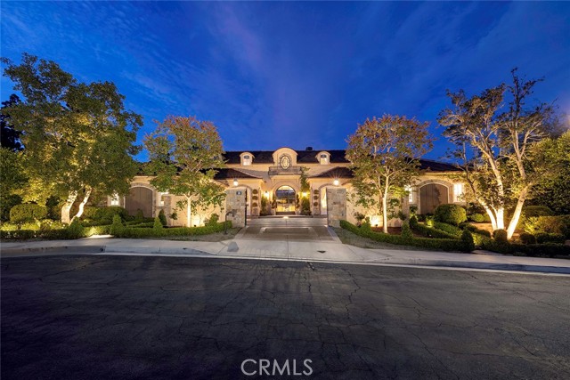 Located in the heart of Big Canyon, this exceptional French inspired estate sits on a large corner lot and is the epitome of spacious indoor-outdoor and single-level living. The stunning custom gated entry leads you into the beautiful entryway where you are greeted with beveled glass on the tall wrought iron doors and a custom chandelier, which opens to the expansive living room. With vaulted ceilings and reclaimed oak beams, the living room showcases custom chandeliers, sconces and wrought iron pocket doors to the inviting rear yard and an alluring antique French limestone fireplace with custom woodwork and a Venetian mirror. Next to the living room is the formal dining area complete with a custom built-in bar and china cabinet, clear ice maker and mini refrigerator, which opens to the spacious kitchen with top-of-the-line appliances including a Wolf microwave, side-by-side Sub-Zero refrigerators, Miele dishwashers and two warming drawers. The chef’s kitchen features custom cabinetry, custom-built hood with plaster and reclaimed oak beam, Calcutta Oro marble countertops, a large island, and pantry with custom iron details and reclaimed wood. Leading to the family room is an antique French limestone fireplace, custom chandelier, and reclaimed oak inlaid ceiling and beams. Within this European estate, the main floor master suite greets you with reclaimed oak beams and French doors to the rear yard, an antique French marble fireplace, custom armoire with a Venetian mirror and dual custom closets. The spa-like bath features Calcutta Oro marble countertops, Swarovski crystal faucets, soaking tub and a chandelier. This master suite also allows for immediate reach to the backyard. The home also enlists three beautiful guest suites with custom closets, an upstairs bonus room or fourth guest suite, dual offices and laundry room. The pleasant ambience continues into the rear yard which is nice for entertaining, with a jacuzzi, water feature and a built-in Lynx barbecue, sink and mini refrigerator. The estate is complete with exquisite custom landscaped gardens, total home automation with Control4 System, Sonos sound system, custom Lutron lighting, water filtration system and central vacuum.