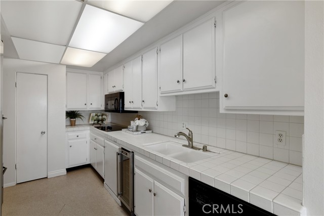 The kitchen is appointed with refrigerator, range, dual-ovens, microwave, dishwasher, wine refrigerator, white cabinetry, ample storage and large panty.