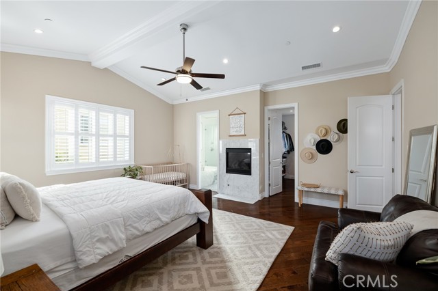 oversized primary bedroom with ceiling fan and fireplace