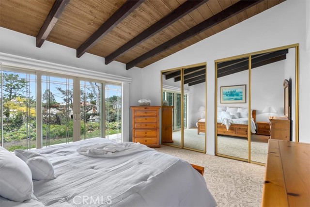 Master bedroom with beamed ceilings and greenbelt views