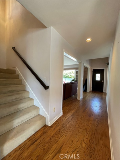 Hallway, with hardwood flooring, and stairs up to bedrooms