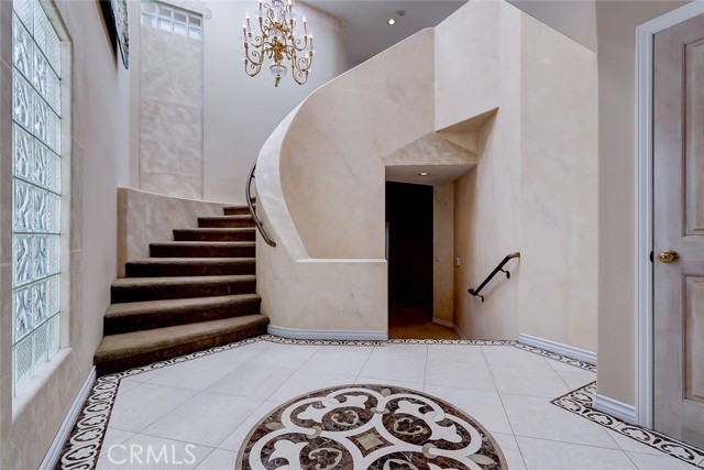  Dramatic front foyer with artistic tile floor design and view of circular stairway leading to upstairs living area