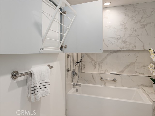 Drying racks for clothes within wall cabinet of primary bathroom.