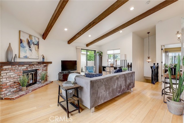 Cozy brick fireplace living room with access to your large outdoor balcony to your left and Primary Suite to the right.