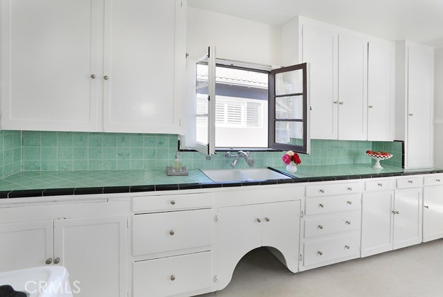 What a sweet kitchen! The vintage tile countertop is in great condition. The upper cabinets are ceiling height, providing lots of storage…and that window!