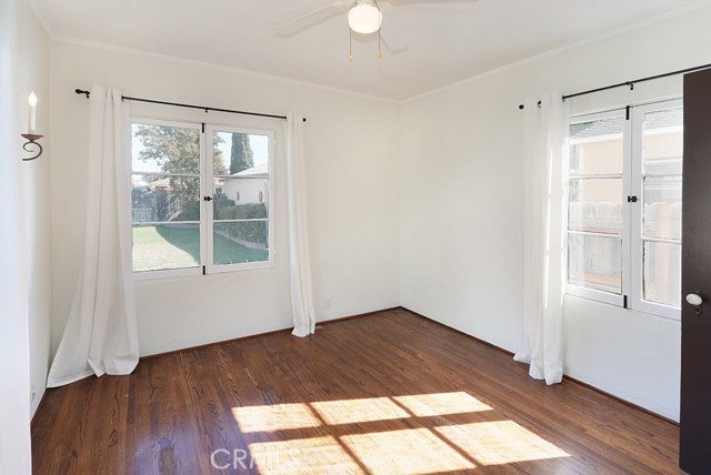 Bedroom #3 overlooks the backyard. Notice the vintage sconce, French mullion windows, original oak floors and original solid wood doors.