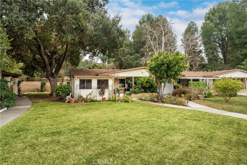 Welcome to one of FRIENDLY VALLEY's most desirable units!  Located just in front of SEVEN guest parking spots, with beautiful lawn in front and oak tree on the side, this end unit has a look and feel of a single family home!  Not included in the square footage is an additional den in front and sun room (with full laundry hookups) in the rear.  The back patio looks out onto the rear of the common grounds, which for years was maintained by owner as their own!  The interior is cozy and bright, with solar tubes providing light throughout during the day.  The HOA common area can be seen from the front porch and is a short walk or drive away!  55+ guard gated community plus the tranquil location mean you have a wonderfully peaceful place to relax and enjoy your private space.  Amenities include walkable golf course, swimming pool, rec room, and lots of activities to choose from.  A must see for anyone looking for 55+ living in Santa Clarita!