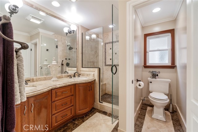 Master bath showing double sinks, stall shower and toilet with privacy door