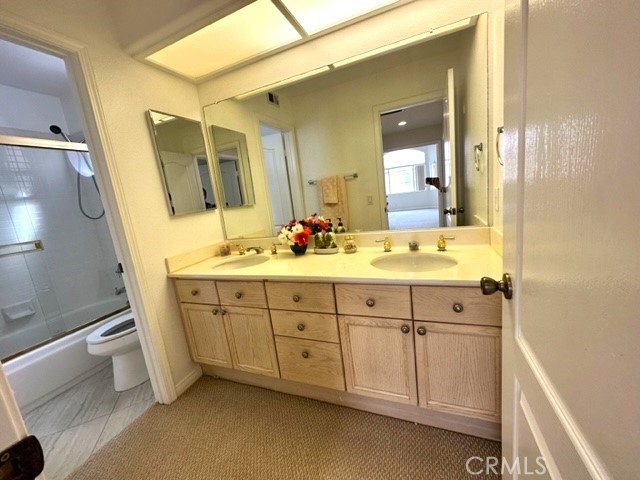 Hall bathroom has double sinks and a separate toilet & bathtub/shower combination with sliding glass door.