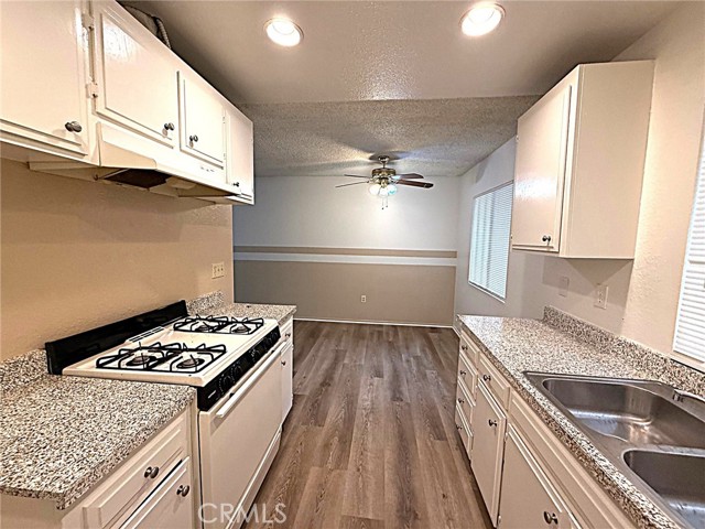 Gas stove, stainless steel sink, white cabinets.
