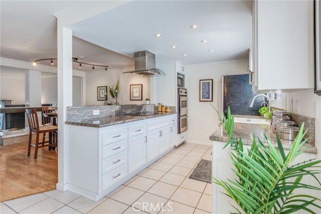 Bright and open remodeled kitchen featuring granite counters, stainless appliances, white shaker cabinets and plantation shutters.
