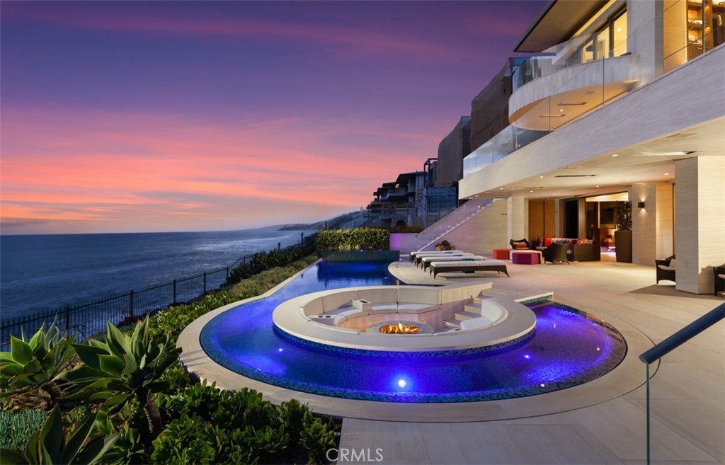 Breathtaking Pacific Ocean views, unprecedented contemporary architecture that is destined to stand the test of time, and a location without compare elevate this modern custom showplace to the top of Southern California's rarified oceanfront real estate. Welcome to the private realm of 7 Strand Beach Drive at The Strand at Headlands in Dana Point, where a premium oceanfront setting dazzles the heart and soul with unobstructed beach, whitewater, sunset and Catalina Island views that stretch from the dramatic Dana Point Headlands up the coast toward the Palos Verdes Peninsula. Towering three levels over the sand, the residence was completed in 2018 by Brown Brothers Construction using architectural plans from C.J. Light and Associates, with interiors by Fullen Enany Design Group and extraordinary custom lighting from Ron Neal Lighting Design. Traverse a bridge that overlooks a courtyard below to the home's gallery-sized foyer, where high ceilings, views to floors above and below, lofty skylights and immediate ocean views set the scene for impressive living and entertaining. A three-level floating staircase is accentuated by in-wall LED lighting and curvilinear wood and glass detailing, creating a grand focal point on every floor. Approximately 9,630 square feet, the exceptionally open and light design presents six ensuite bedrooms and seven- and one-half baths, including two primary suites and a junior suite on the top level and another junior suite on the bottom floor. Both primary suites offer sunny ocean-view decks and freestanding bathtubs, while the main suite enhances luxury with dual walk-in closets and separate vanities. Large expanses of the residence are primed for entertaining, including a great room, dining room, and a kitchen with a chef's pantry on the main level. The lower level is phenomenal. Enjoy a lounge, wet bar, home theater, and wine room. Disappearing glass pocket doors eliminate boundaries between indoor living areas and outdoor spaces that include a stunning pool with a spa and a sunken open-air fireplace with built-in seating. A commercial grade elevator with window serves all floors, and Crestron smart-home technology, a solar power system, home-scent tech in the HVAC system, and exotic stone and wood finishes lend the home a sophisticated aura that is unrivaled on the coast. The Strand is a private, gate-guarded oceanfront enclave boasting over one mile of coastline, 70 acres of parks, a beach club, and more.