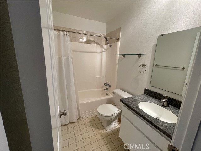 A nice bathroom equipped with a shower/tub, granite counter and tile floor!