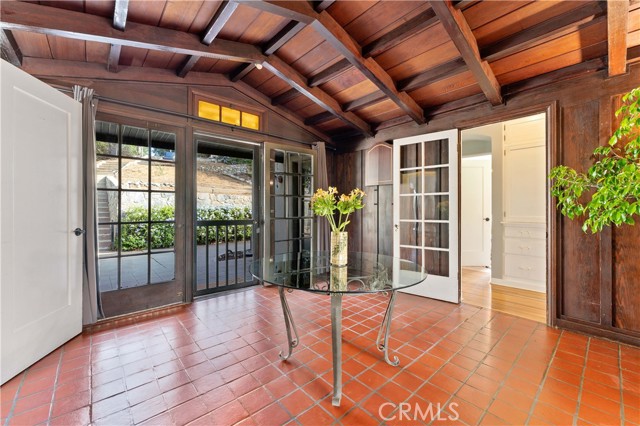 Large entrance with French doors, terra-cotta floors and wood beam ceilings.