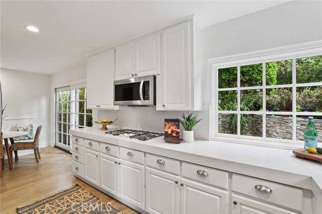 The kitchen features stainless steel appliances and a delightful breakfast nook, with a sliding glass door for easy access to the side patio and BBQ area.