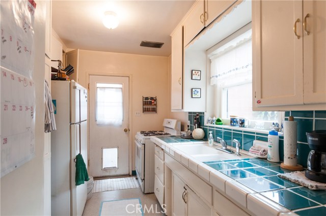 Really nicely upgraded kitchen tile. This window is looking north into backyard. Lots of storage! Side door to west facing walkway.