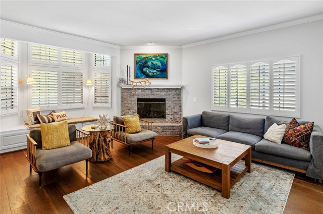 Living room with 12 foot ceilings, plantation shutters, hardwood floors, bay window and tiled fireplace.