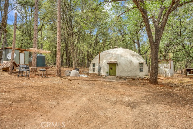 Privacy Found on Almost 5 Acres! Set amongst Black Oak, Live Oak & Ponderosa Pine trees, a unique Dome house with energy efficient improvements awaits! Enter the home to find a cozy living room with wood burning stove, ceiling fan, concrete flooring & radiant/hydronic heat system. Loft upstairs has potential for additional living space or even a 3rd bedroom. Newly remodeled kitchen is open to the living room and includes modern conveniences such as floating shelving, new cabinetry and countertops, newer refrigerator, dishwasher, electric range and garbage disposal. 2 main level bedrooms with ceiling fans and 2 bathrooms that have been remodeled with redwood countertops. Indoor laundry with floating shelving & newer multi-point lock door that leads you outside. Brand new electric water heater! Multiple sheds can be found on the property for all of your storage needs. The large chicken coop/run is a bonus! This completely private property lends itself to the self sustaining lifestyle that you have been dreaming of.