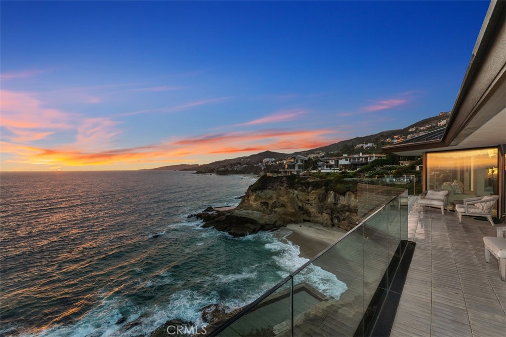 Welcome to one of the world’s finest oceanfront estates, where a rare double bluff-top homesite of nearly 20,000 s.f. and a fully rebuilt custom residence combine to create the most unique living environment in Laguna Beach. Premium northwest-facing views capture the ocean, beach, crashing waves, shimmering lights, and Catalina from every room of the contemporary masterpiece in guard-gated Three Arch Bay. A dramatic promontory setting is secluded behind a custom entry gate and features a circular drive, park-like grounds, and a spacious courtyard. Wraparound view decks offer steps down to bedrock, where a private saltwater pool is replenished naturally with the tide. Neither the location—which spans 150' at the water’s edge—or the pool would be granted permission by today’s codes, making this a truly rare opportunity. Approx. 5,144 s.f. with 4 bedrooms, 5 full baths, and 2 half baths, the open and airy residence showcases soaring ceilings, a seamless living and dining area, a home theater, an extensive glass-enclosed wine storage wall, and a sleek kitchen with enormous island and top-end appliances. Just inside the entry gate, a separate structure is ideal as a gym, studio, or office.