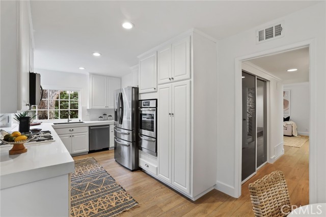 The kitchen features stainless steel appliances and a delightful breakfast nook, with a sliding glass door for easy access to the side patio and BBQ area.