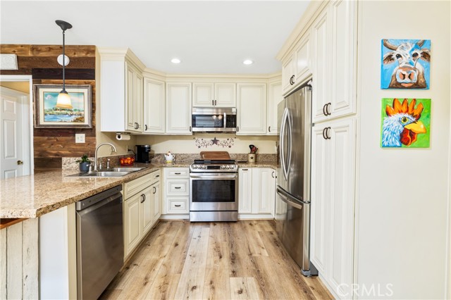 Inside kitchen. Laminate wood floors, custom cabinetry, granite countertops, stainless steel appliances.