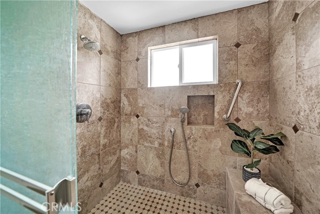  Walk-in shower with tile surround, dual shower heads, and seating.