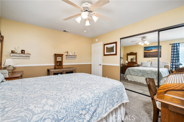 Bedroom 1 second angle showing mirrored closet door and ceiling fan.