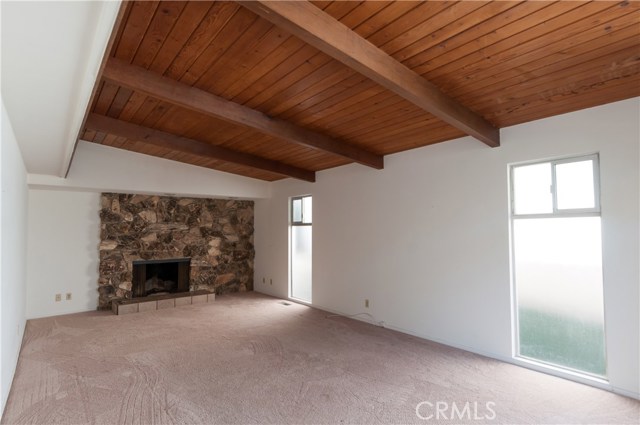 Good sized living room with beams and rock fireplace.