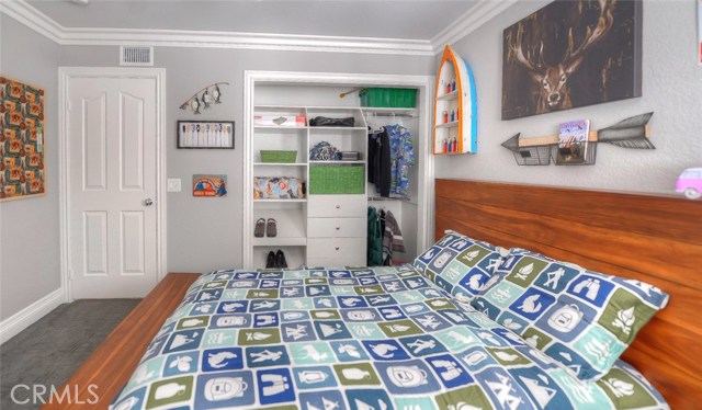 One of the upstairs bedrooms with closet organizers, crown molding, ceiling fan, and plantation shutters.