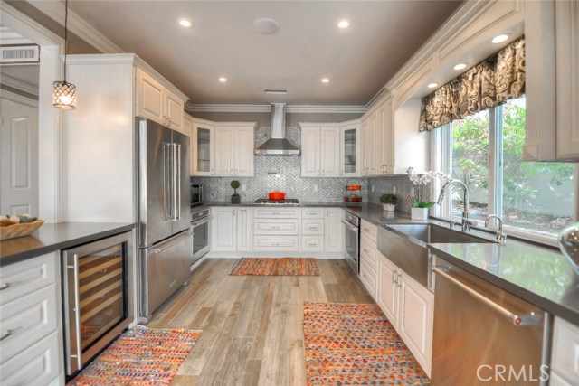 Remodeled kitchen with dual ovens, farm sink, five burner gas cook top, pot filler over cook top, wine fridge, white cabinets with pull out shelving.