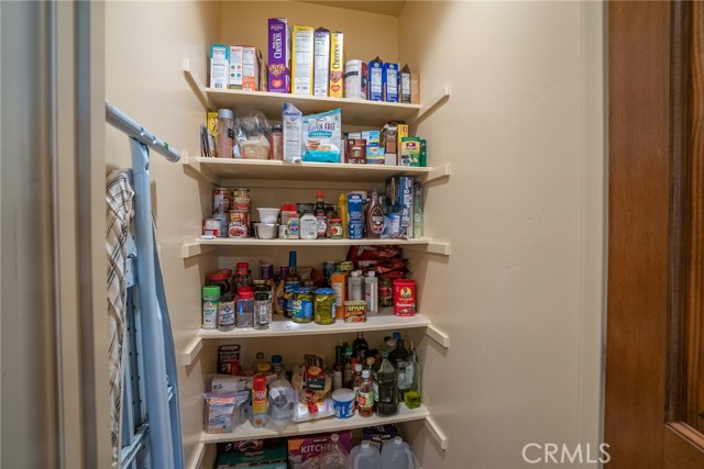 Next to the kitchen is a walk in pantry with shelves and light.