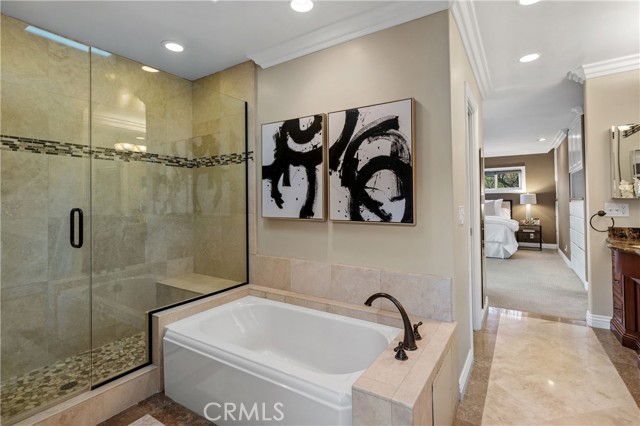 An elegant en-suite bath with gorgeously tiled and frameless oversized shower, soaking tub and the vanity with dual sinks.