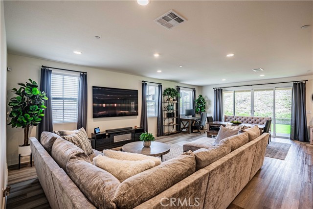 Family room side of the great room that opens to the kitchen has recessed lighting, wood laminate flooring with pocket sliding glass doors that leads to your outdoor porch and new astroturf lawn.