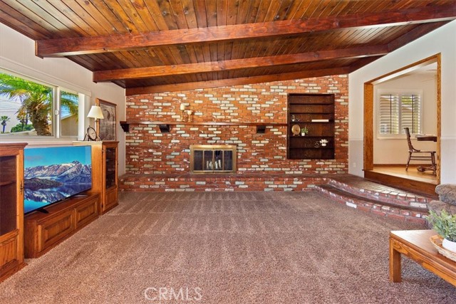 Family room with wood beamed ceiling and used brick fireplace.