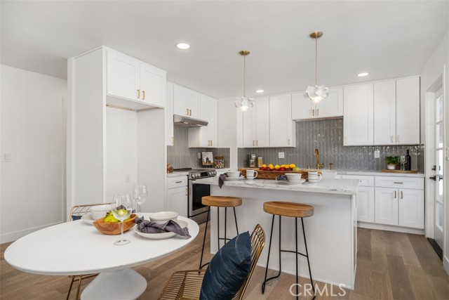 The dining area and into the kitchen which features an island( with breakfast bar), new cabinets, counter tops, stainless steel appliances and tile back splash.