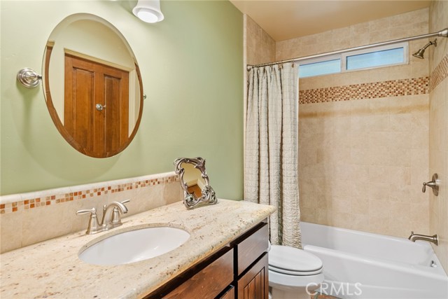 The main bathroom is on the opposite side of the home from the primary suite.  It features a granite countertop and  handsome tiled tub/shower combo.