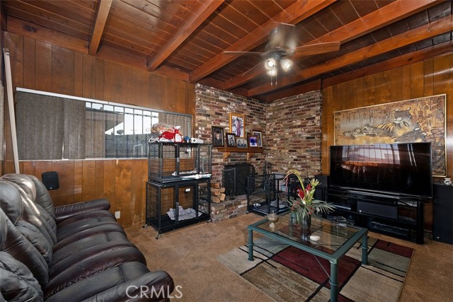 Family room w wood beams and large brick fireplace (dog crates present)