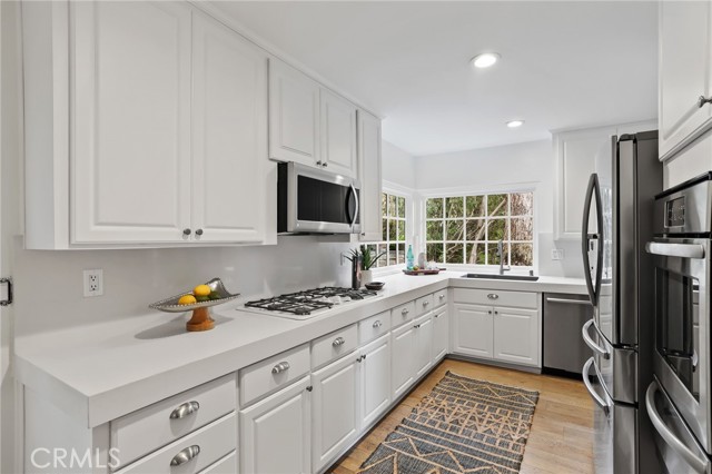 The kitchen features stainless steel appliances and a delightful breakfast nook, with a sliding glass door for easy access to the side patio and BBQ area.