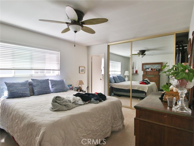 The master bedroom showing the ceiling fan mirrored wardrobe doors and in the rear, the entry to the attached master bath.