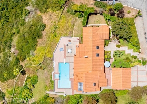 Aerial view above home showing lower grass area, side gated grass area, pool and home