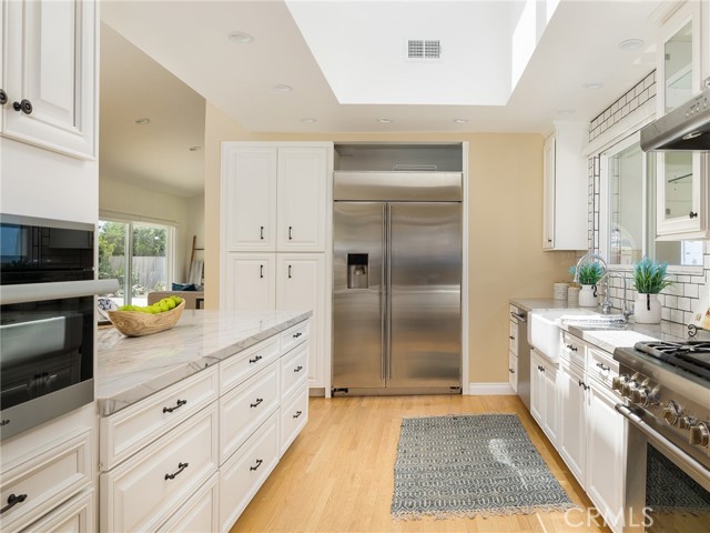 Gourmet kitchen offers quartzite counters, wine fridge, stainless steel appliances, large skylight and recessed lighting.