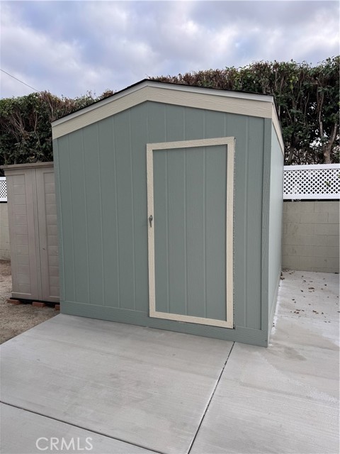 SHED WITH SHELVING NEAR THE END OF CARPORT