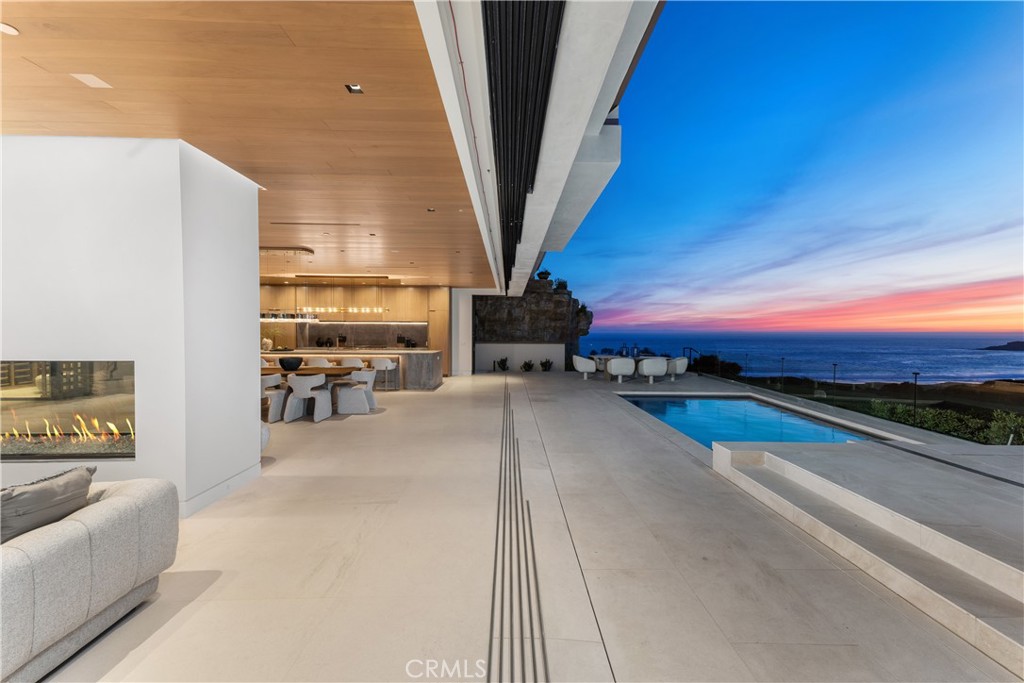 Brand new and completed in May 2025, 13 Ritz Cove Drive is a custom-built oceanfront estate located in the exclusive guard-gated community of Ritz Cove. This architectural masterpiece is the result of a prestigious collaboration between renowned architect Mark Teale, acclaimed interior designer Megan Crane, and respected builder Tom Nicholson. Together, they have crafted a one-of-a-kind coastal residence that blends timeless elegance with modern sophistication. Positioned on a rare front-row homesite with unobstructed views of the Pacific Ocean, Catalina Island, and the white sands below, the home offers approximately 8,000 square feet of refined living space with 6 bedrooms and 6.5 bathrooms. Designed to maximize light, views, and indoor-outdoor living, nearly every room captures dramatic ocean panoramas. Inside, the home features a grand pivot entry door, expansive limestone flooring, custom-stained walnut ceilings, and an ocean-facing great room with a signature 10’ x 30” Stellar fireplace. The gourmet kitchen is outfitted with Wolf and Sub-Zero appliances, Dorn Bracht fixtures, and bespoke cabinetry. A 450-bottle, climate-controlled wine room serves as a focal point for entertaining. Two ocean-view primary suites each include spa-style bathrooms with steam showers and private terraces. Additional amenities include a Savant audio system, Lutron lighting controls, comprehensive security system, sculptural limestone stair wall, and a saltwater splash pool with integrated water feature. With direct beach access and just moments from the Ritz-Carlton, Waldorf Astoria Monarch Beach, and top-tier golf and dining, this newly completed estate offers a rare opportunity to own a legacy property in one of Southern California’s most prestigious coastal communities.