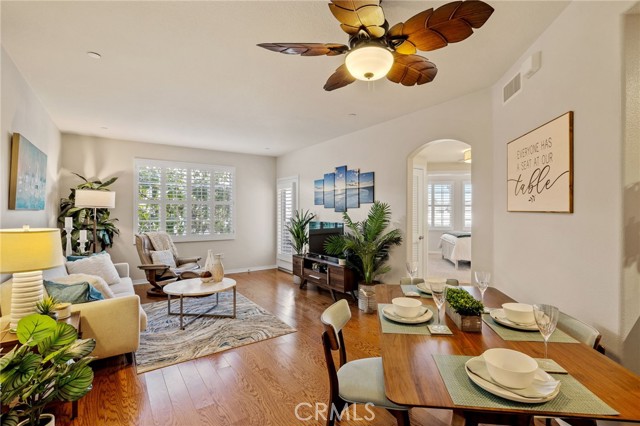 Warm-toned flooring adds contrast to the light and bright interior of living area...dining area in foreground, living area in background with door to balcony.