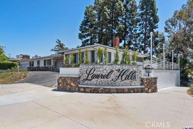8346 Mulholland Drive Los Angeles, California Location, location, location! Tucked into the sprawling Laurel Hills of Los Angeles is a gorgeous 2,801-sqft corner home enhanced with new fresh paint and brand-new flooring throughout. A circular driveway paves the way into a spacious and light filled abode encompassing a large entryway, formal living room with a stone face fireplace, a multipurpose living room with a center island for bar stool seating, and a large family room featuring a full wet bar to unwind after a long day of work. Very spacious rooms with a cohesive flow from one room to the other creates plenty of entertaining space. The gorgeous kitchen delights in granite countertops with all stainless-steel appliances which include refrigerator, dishwasher, and stove while also housing great built-in features plus an intimate breakfast nook. Each bedroom relishes in ample built-in storage and the primary bedroom includes a large bathroom with two sink vanities, shower stall, and a step-down tiled bathtub. The property includes both a washer and a dryer unit plus central A/C to keep the space cool and comfortable all year. Outside, new paving along the side yard and expansive backyard provides additional room for entertaining and creates a private oasis offering stung views of the San Fernando
