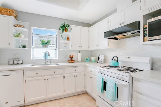 Cheerful sunlight through a mini-bay window over the sink complements this pristine white upgraded Kitchen.