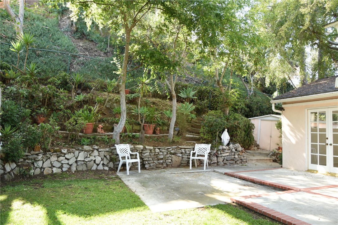 Super private rear yard with grass, rock wall, planting areas, and patio.