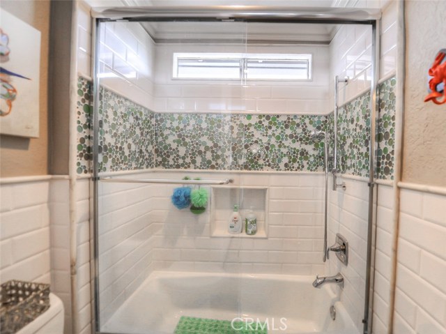 A look at the shower enclosure in the upstairs hall bathroom - with glass bubble tile, white subway tile and marble accents.